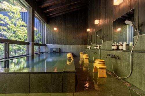 uma grande casa de banho com um chuveiro e um lavatório em Bessho Onsen Midoriya em Ueda