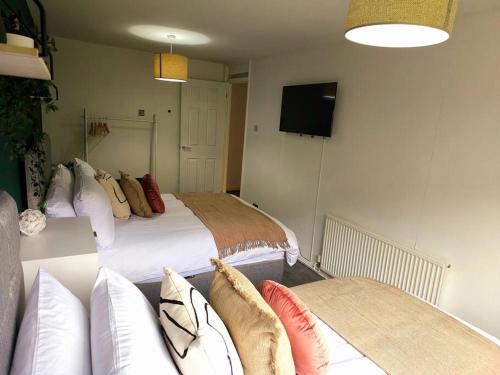 a bedroom with two beds and a tv and a couch at Homebird Property - Buckton House in Leeds