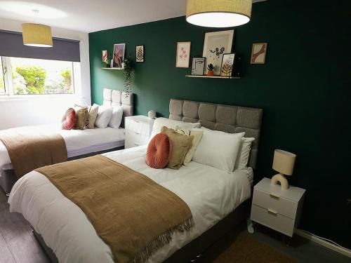 a bedroom with two beds and a green wall at Homebird Property - Buckton House in Leeds
