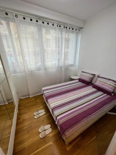 - une chambre avec un lit et une paire de chaussons dans l'établissement Jardin sur la Promenade des Anglais, à Nice