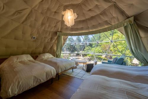 two beds in a room with a large window at Bessho Onsen Midoriya in Ueda