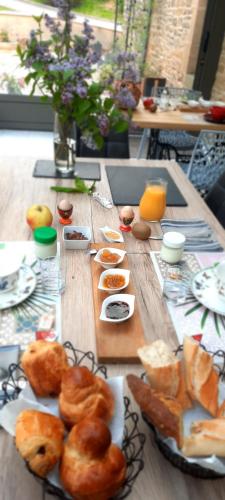 a wooden table with bread and pastries on it at Les étangs du moulin d'Harcy in Lonny