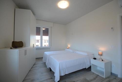 a white bedroom with a white bed and a window at FABIO a Marina di Pisa in Marina di Pisa