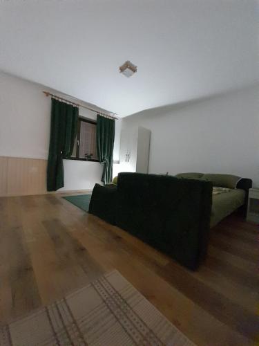 a living room with a black couch and a wooden floor at Bajka in Valjevo