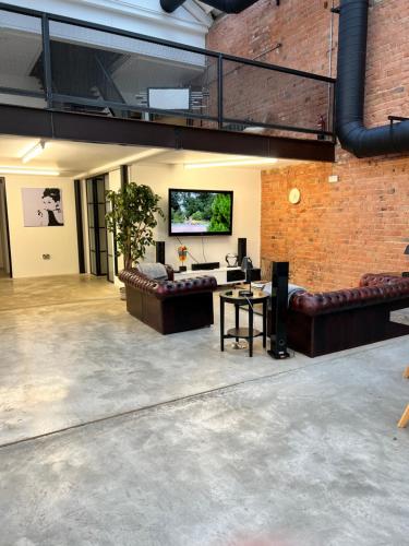 a living room with leather couches and a flat screen tv at Bedford Street Lofts in Leamington Spa