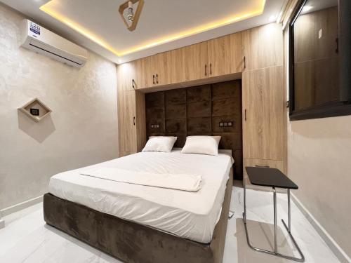 een slaapkamer met een bed met een houten hoofdeinde bij Appartement VIP Panoramic Sea view et deluxe in Al Hoceïma