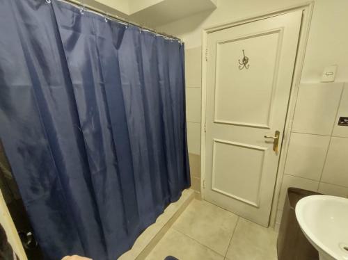 baño con cortina de ducha azul y lavamanos en Mahatma Hostel, en Santiago