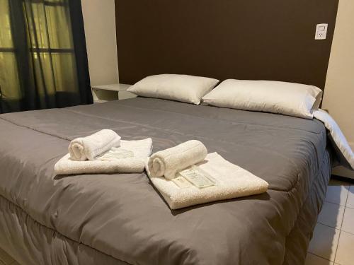 Una cama con toallas y almohadas encima. en Una casa amplia y centrica en Tunuyán