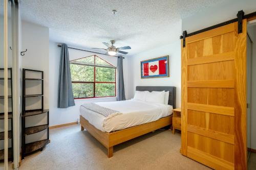 een slaapkamer met een bed en een houten deur bij Cozy Creekside Two-Storey Condo in Whistler