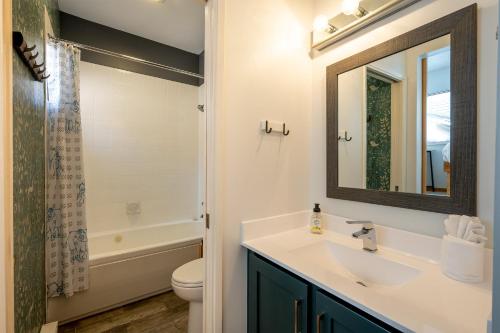 een badkamer met een wastafel, een toilet en een spiegel bij Cozy Creekside Two-Storey Condo in Whistler
