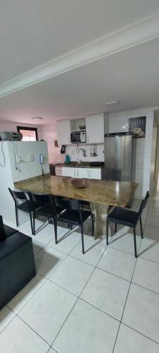 una cocina con una gran mesa de madera y sillas negras en Ótimo apartamento com wi-fi gratuito, en Guarapari