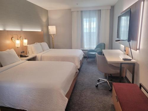 a hotel room with two beds and a desk and a television at DoubleTree by Hilton Houston Westchase in Houston