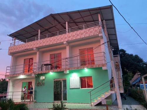 una casa con balcón y personas sentadas en el balcón en Casa Guiwa Hostel, en Palomino