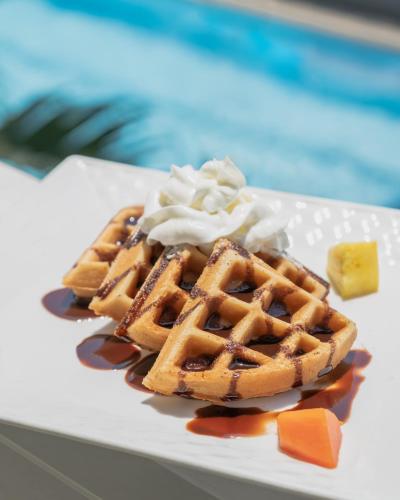 Un plato de gofres con crema batida y almíbar en Hotel Roca Sunzal, en La Libertad