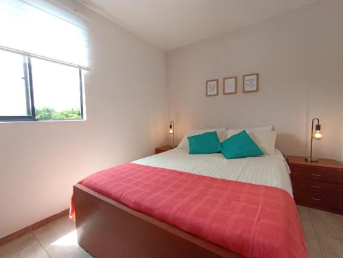 a bedroom with a large bed with a red blanket at Apartamento Eje Cafetero - hermosa vista a piscinas in La Tebaida