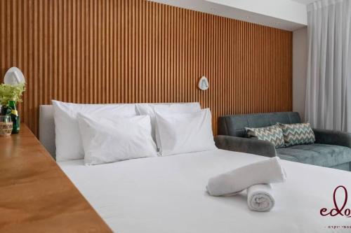 - une chambre avec un lit blanc et un canapé dans l'établissement דירה יוקרתית 100 מטר מהים - By Edom, à Eilat