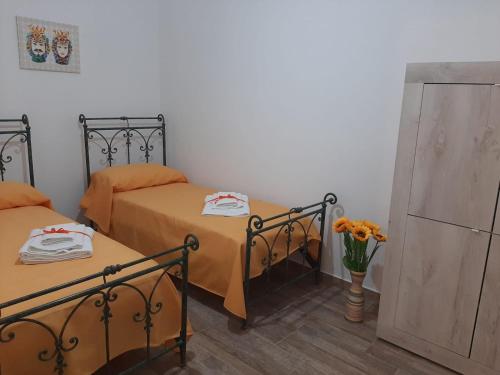 duas camas num quarto com um vaso de flores em Casa vacanze Il Girasole em Bagheria