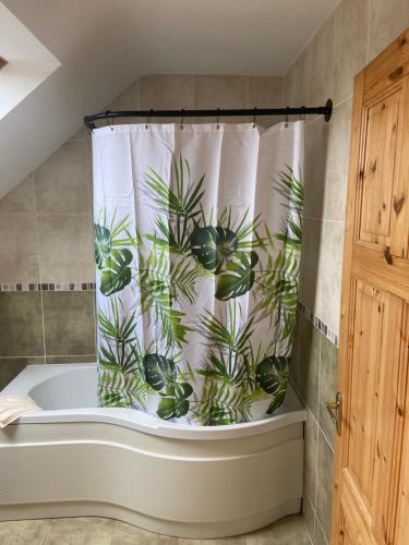 a bathroom with a shower curtain with plants on it at Irish Isle Oasis: Spacious 5-Bedroom Retreat in Bungowla