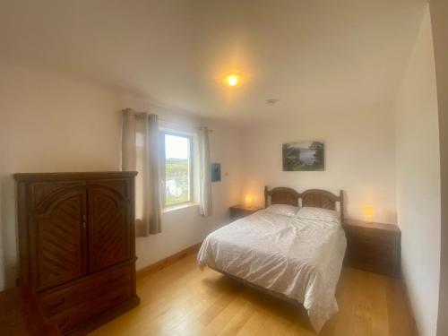 een slaapkamer met een bed, een dressoir en een raam bij Irish Isle Oasis: Spacious 5-Bedroom Retreat in Bungowla