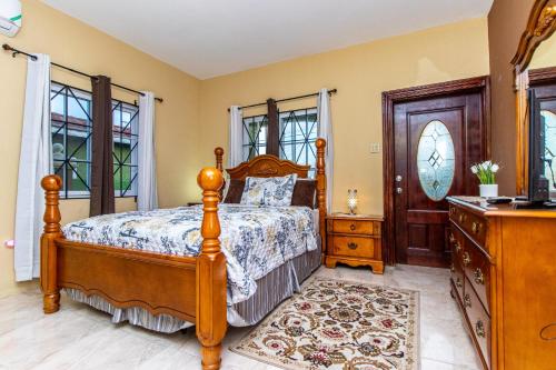 a bedroom with a bed and a dresser and windows at J&R Sunshine Retreat in Spanish Town