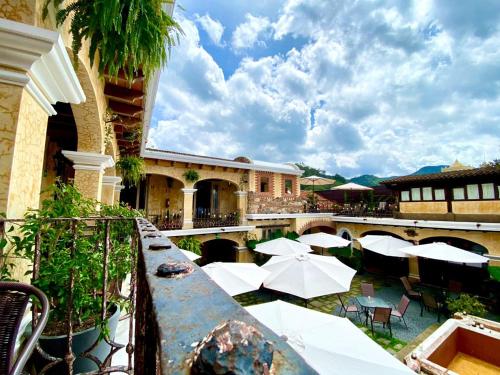un patio extérieur avec des parasols, des tables et des chaises dans l'établissement Hotel Casa Realeza, à Antigua Guatemala