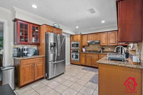 a kitchen with wooden cabinets and a stainless steel refrigerator at San Gabriel Stunner - An Irvie Home in Albuquerque