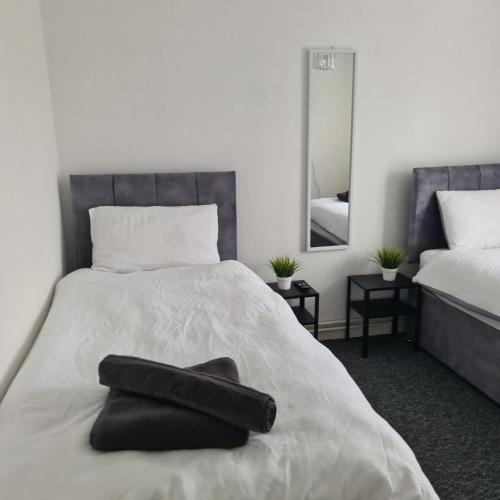 ein Schlafzimmer mit einem Bett mit einem schwarzen Handtuch darauf in der Unterkunft Freshen-Up Stays in Oakengates