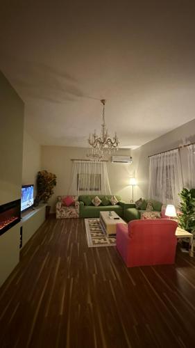 salon z zieloną kanapą i czerwonym krzesłem w obiekcie فيلا ممشى الضباب w mieście Abha