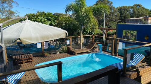 インビトゥバにあるCasa Container Praia do Rosa - 01 Ibiraqueraの椅子2脚と傘が備わったプール