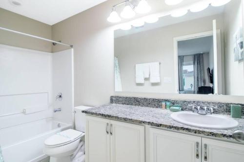 La salle de bains est pourvue d'un lavabo, de toilettes et d'un miroir. dans l'établissement 5 mins from Disney, Family Friendly Townhome, à Kissimmee
