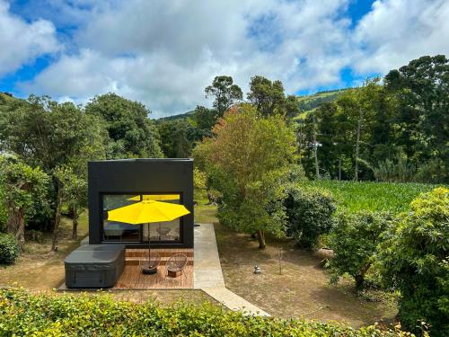 a black house with a yellow umbrella on a deck at Villa Várzea - The Black Cabin in Várzea
