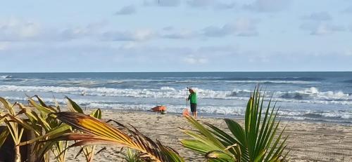 a person standing on the beach with a dog at QUINTA DIAMANTE villas&hotel in Barra Vieja