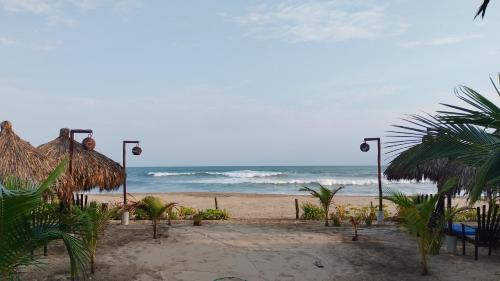 a beach with a straw hut and the ocean at QUINTA DIAMANTE villas&hotel in Barra Vieja