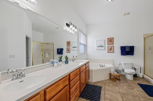 ein Badezimmer mit zwei Waschbecken, einer Badewanne und einem WC in der Unterkunft Burnside Beauty 4BR Pingpong Patio in Tallahassee
