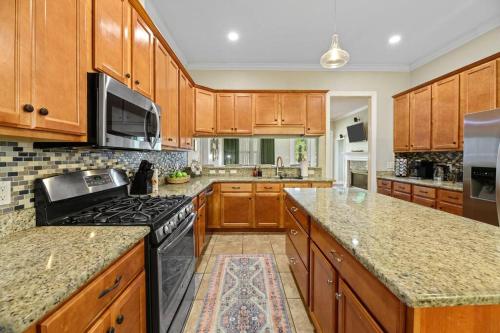 a kitchen with wooden cabinets and a black stove top oven at Burnside Beauty 4BR Pingpong Patio in Tallahassee