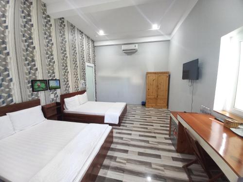 um quarto de hotel com duas camas e uma televisão em Khách Sạn Chấn Phú Quý em Phú Quý