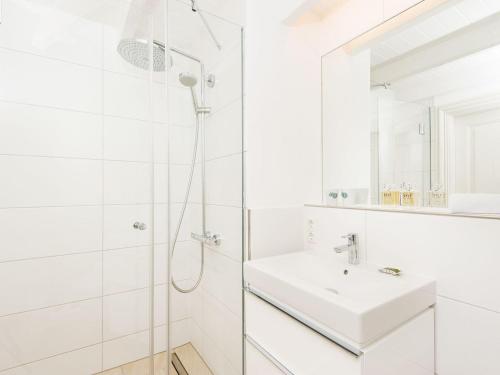 La salle de bains blanche est pourvue d'un lavabo et d'une douche. dans l'établissement Dorfaue, à Kampen