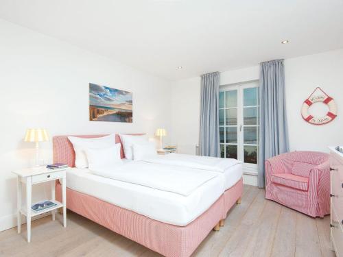 a bedroom with a large bed and a pink chair at Salig-Hues in Kampen