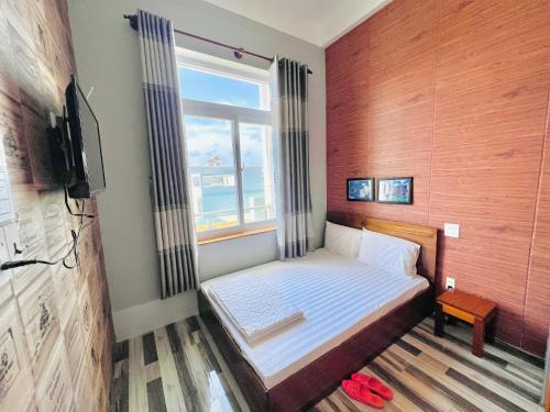 um pequeno quarto com uma cama e uma janela em Khách Sạn Chấn Phú Quý em Phú Quý