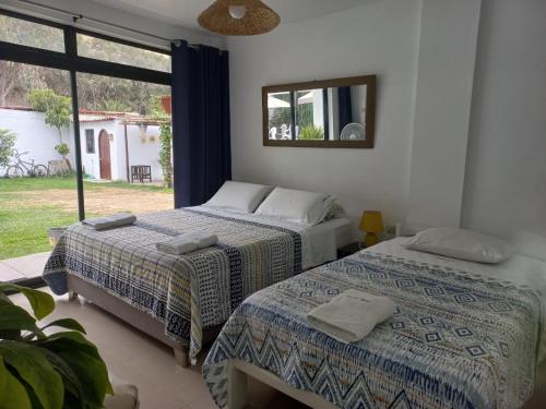 two beds in a room with a window at Montemar Apart Hotel - Playa Huanchaco in Huanchaco