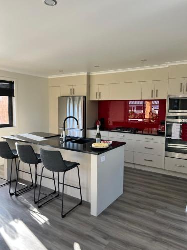 a kitchen with white cabinets and a island with chairs at MataMata in Matamata