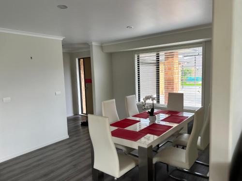 a dining room with a table and white chairs at MataMata in Matamata