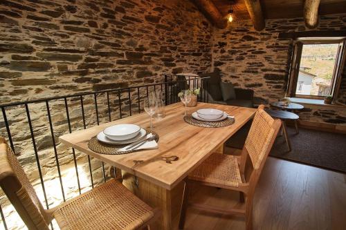 a wooden table with plates and wine glasses on it at A Barreira -Lar da cima- in Folgoso
