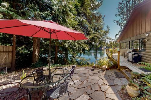 a patio with a table and a red umbrella at Lake Benson Rendezvous in Grapeview
