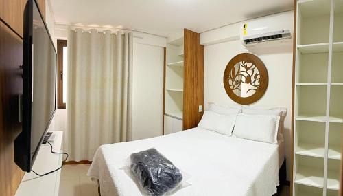 um quarto com uma cama branca e uma televisão em Apto Facilties 250m Praia Ponta Verde Luxo em Maceió