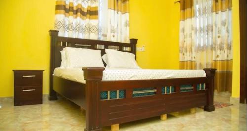 a bedroom with a wooden bed with a yellow wall at Extended stay suite, Tema. in Ashaiman