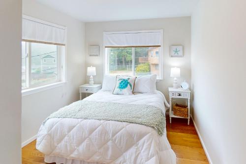 um quarto branco com uma cama e 2 janelas em Island Cottage em Madrona Beach