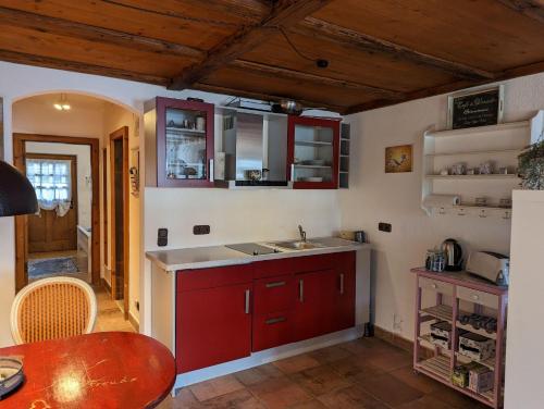 a kitchen with red cabinets and a sink and a table at Herzstuecke-Ferienwohnung in Ingenried
