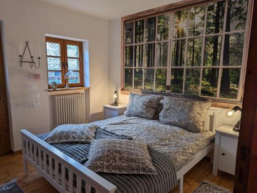 Herzstuecke-Ferienwohnung في Ingenried: غرفة نوم مع سرير مع مجموعة من النوافذ