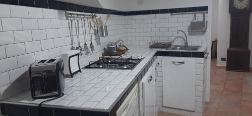 a white tiled kitchen with a stove and a sink at Casa Lale in Corchiano